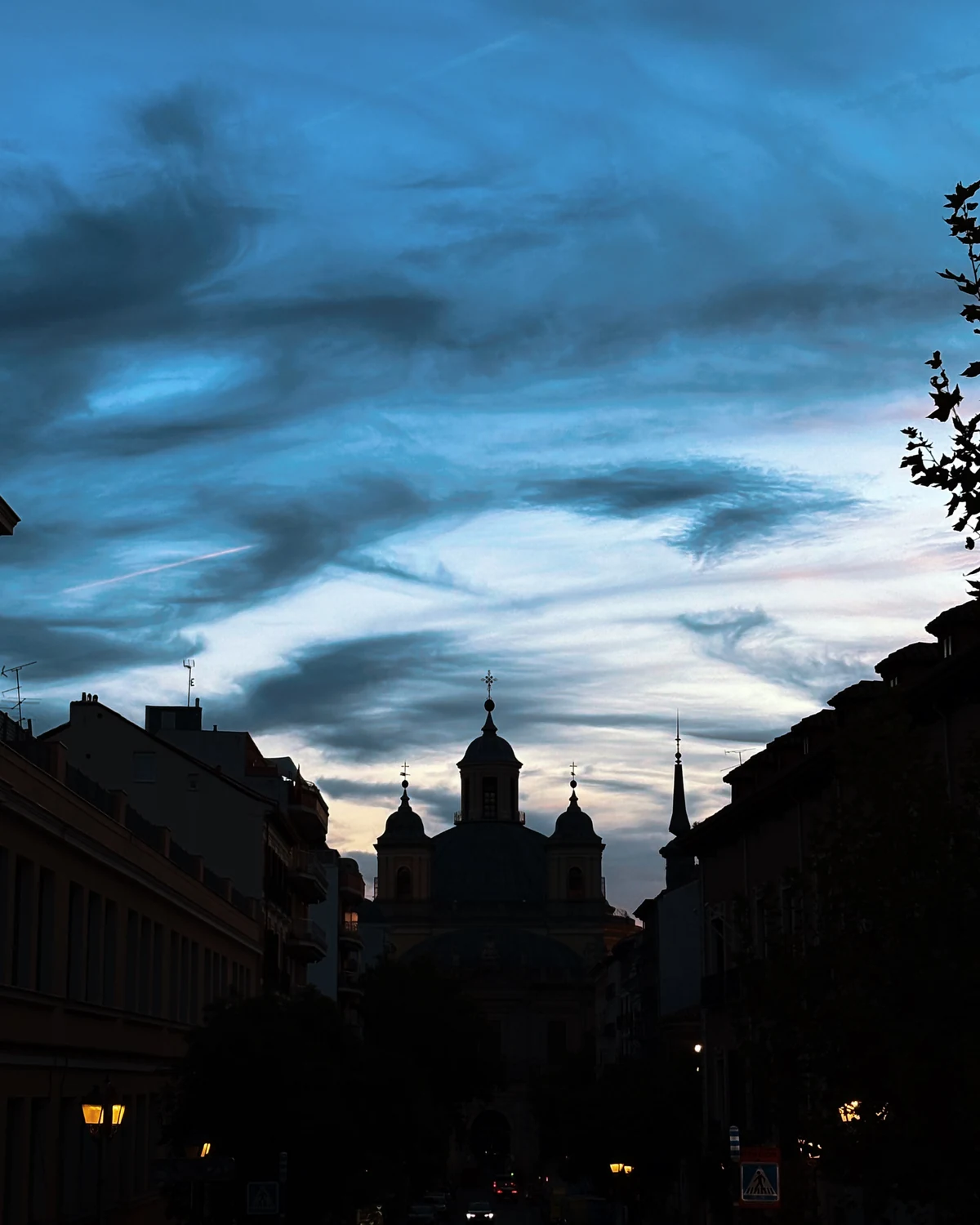 Blue dusk cloud over a domed church silhouette at the end of a street