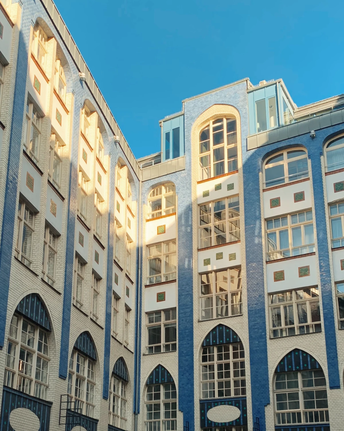 Blue-tiled courtyard facade with arched windows and warm evening light