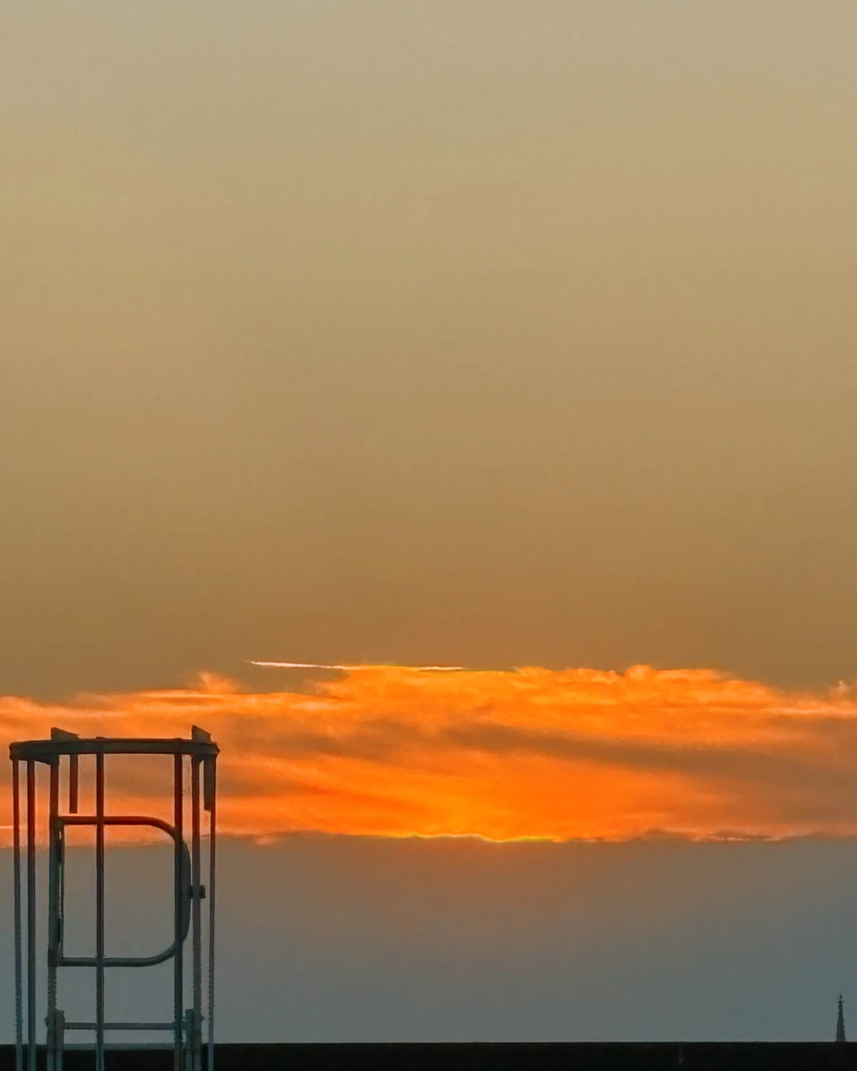 Orange sunset sky behind the silhouette of a rooftop water tower