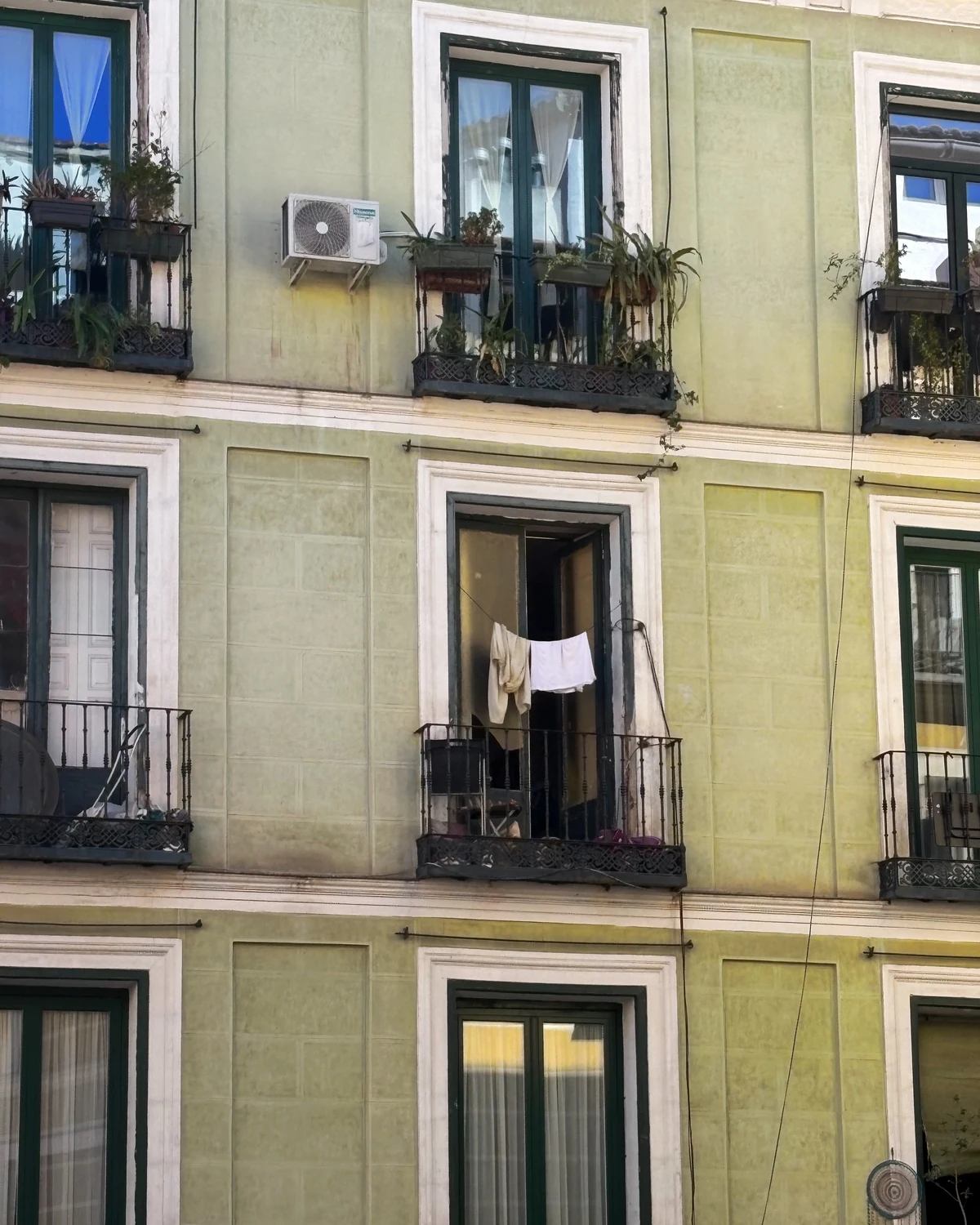 Pale green building facade with laundry hanging on a balcony clothesline