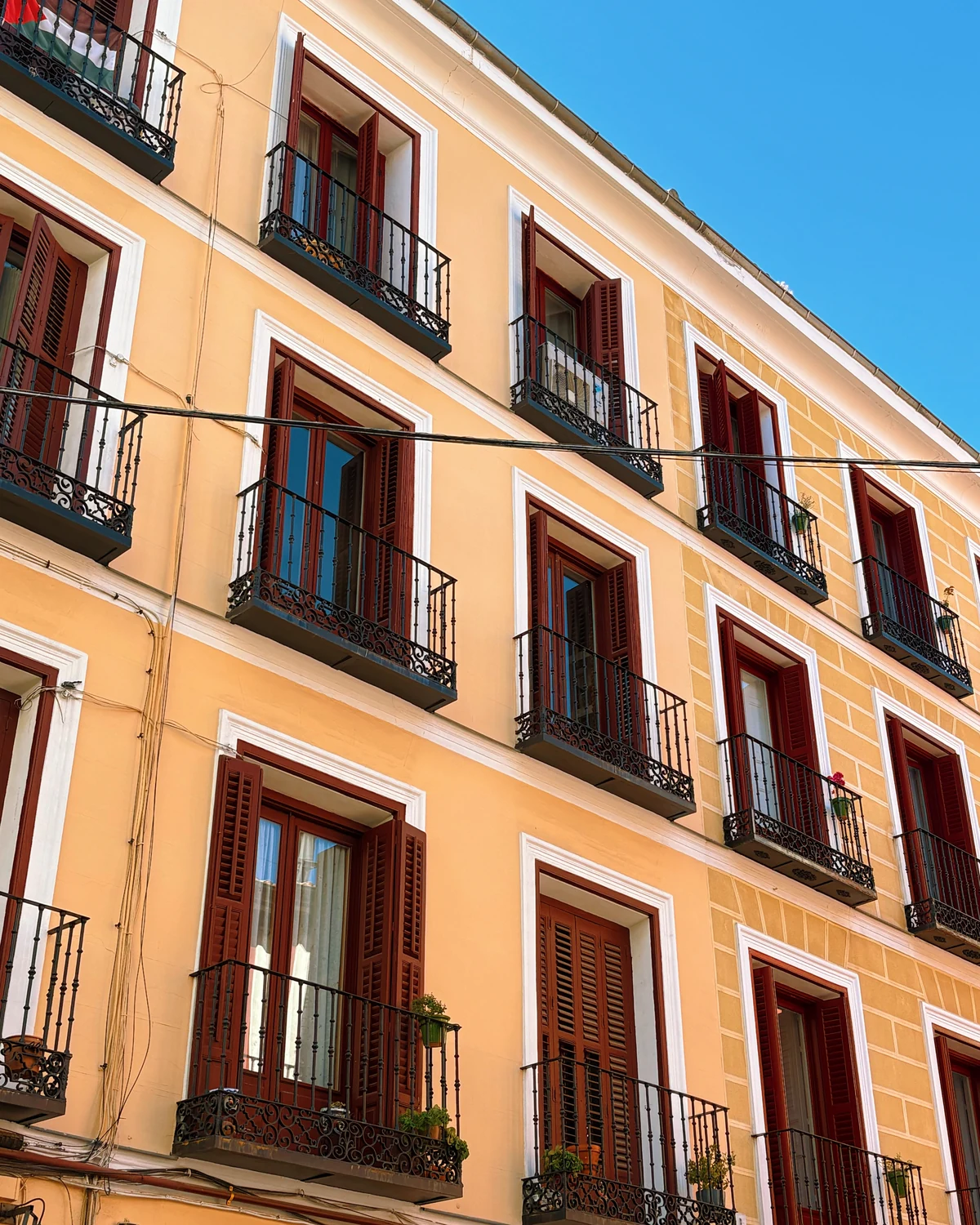 Peach-orange building facade with dark red-brown window shutters