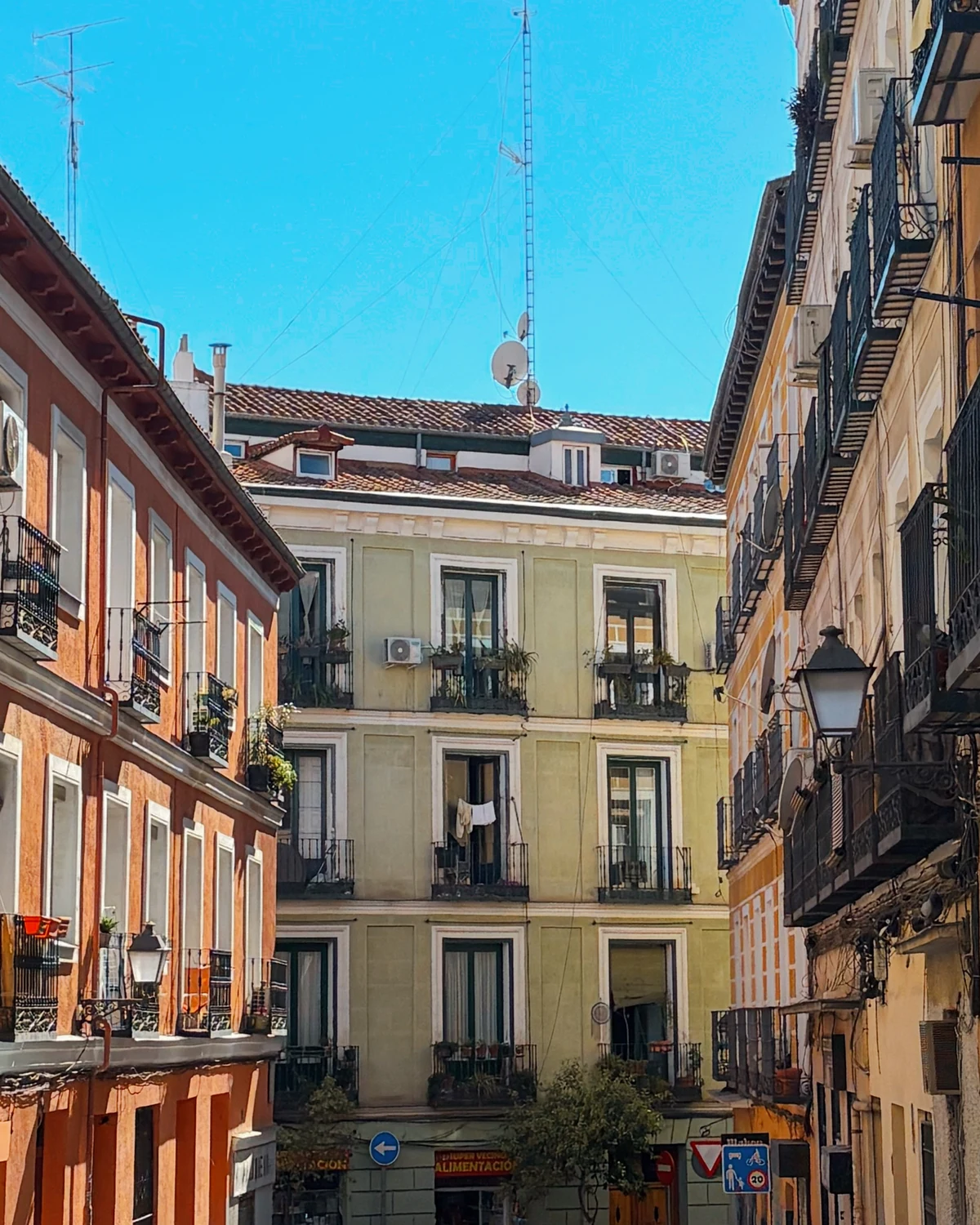 Street canyon of orange and yellow buildings framing a pale green building under blue sky